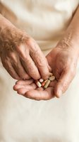 Senior adult hands holding assorted medication pills and capsules, representing healthcare, wellness, pharmaceutical treatment, and daily vitamin supplementation routine.