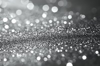Shimmering silver glitter particles create magical bokeh effect on dark background, soft focus abstract macro photography with dreamy sparkles and light dots.