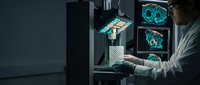 Medical researcher analyzing brain scans on multiple monitors in modern laboratory for neurological diagnosis and treatment planning.