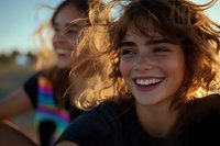 Young woman with curly hair laughing joyfully at sunset, wind blowing through her hair, genuine happiness and carefree moment captured in warm golden light.