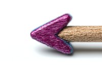 Purple heart-shaped pencil tip macro shot against white background, showing detailed wood texture and vibrant color. Creative education and art concept.