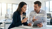 Two professionals, a woman with dark hair wearing a dark blazer and a man with dark hair wearing a light shirt, discuss digital tablet in modern office with holographic interface overlay and windows in background.