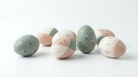 Pastel Easter eggs in sage green and blush pink with delicate floral patterns scattered on white background for spring holiday decorating and crafts.