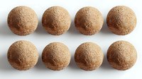 Homemade chocolate truffles dusted with cocoa powder arranged in two neat rows on white background, isolated confectionery ready for packaging and design use.