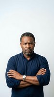 Middle-aged African American man wearing navy button-up shirt with arms crossed, displaying confident posture against white background. Suitable for corporate, business, and professional portraits.