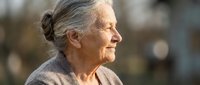 Senior woman with gray hair in profile, smiling outdoors in natural daylight. Suitable for healthcare, wellness, aging, lifestyle and senior living concepts.