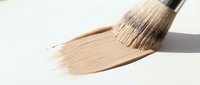 Paintbrush with natural bristles applying beige stroke on white surface, suitable for art, design, and creative projects.