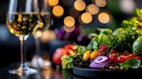 Fresh colorful vegetables and fruits arranged on dark plate with glass of white wine and soft bokeh lights in background, romantic dinner setting.
