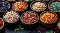Variety of colorful lentils and legumes in wooden bowls arranged in rows, fresh herbs scattered around, dark moody background for food photography.