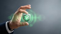 Businessman hand holding glowing green shield icon with digital security symbol, representing data protection and cybersecurity solutions for business.