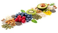 Healthy superfood ingredients including avocado, berries, nuts, seeds and oats arranged in colorful row on white background for nutrition concepts.
