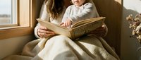 Mother and child reading together by sunny window, cozy family bonding moment with warm natural light creating peaceful home atmosphere for storytelling.