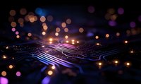 Glowing circuit board paths with purple and orange bokeh lights creating futuristic technology background with depth of field effect and digital connectivity concept.