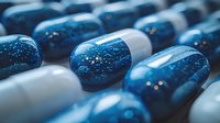 Macro shot of blue and white medical capsules with glitter effect creating a dreamy pharmaceutical background perfect for healthcare and medicine concepts.