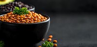 Fresh chickpeas in black ceramic bowl garnished with parsley on dark background. Raw legumes and herbs composition with copy space for text.
