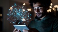 Young African American man smiling while using tablet with glowing blue network hologram projection emerging from screen, bokeh lights in dark background.