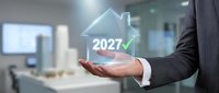 Real estate agent holding holographic house icon with 2027 and checkmark above palm, symbolizing future property investment, growth projections, and successful home buying goals.