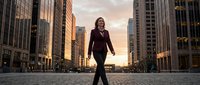 Professional businesswoman walking confidently through urban financial district at sunset, corporate success and leadership concept for business presentations.