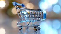 Empty miniature shopping cart against blurred bokeh lights background in cool blue tones, symbolic of online shopping and retail business concepts.