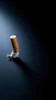 Extinguished cigarette butt with ash on dark blue surface representing smoking cessation and health awareness campaigns.