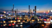 Industrial oil refinery complex at twilight with colorful bokeh lights and mountain backdrop for energy sector presentations and corporate materials.