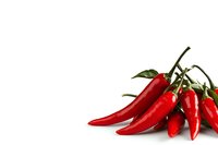 Fresh red hot chili peppers with green stems and leaves isolated on white background, ready for food packaging design and culinary projects.