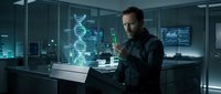 Male scientist examining green test tube in futuristic laboratory with holographic DNA helix display for biotechnology research and genetic engineering concepts.
