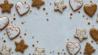 Festive homemade cookies in heart and star shapes with gold glitter and white icing arranged as frame on light background for holiday celebrations.