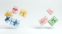 Colorful gift boxes with ribbons floating against white background, isolated presents in pastel pink, yellow, blue and green for holiday celebrations, birthdays and special occasions.