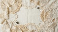 Vintage lace trim collection with delicate crochet borders and pearl buttons on cream fabric background for crafting and sewing projects.