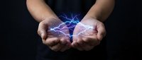 Hands holding glowing electric energy with blue lightning bolts between palms against dark background, representing power, innovation, and technology concepts.