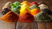 Colorful spice piles arranged on rustic wooden surface including turmeric, paprika, pepper and herbs. Fresh basil leaf adds natural accent to vibrant seasoning display.