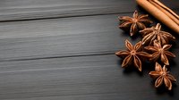 Aromatic star anise and cinnamon sticks on dark wooden background with copy space for seasonal cooking and baking recipes.