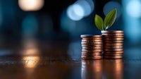Growing plant sprout on stacked coins against blurred blue background, representing financial growth, investment success and sustainable business development.