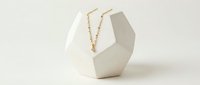 Geometric white jewelry display stand with gold chain necklace, isolated on neutral background. Suitable for e-commerce, retail, and jewelry marketing materials.