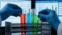 Laboratory scientist in blue gloves conducting viral indicator data analysis with colorful test tubes and digital charts for medical research and diagnostics.