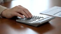 Professional accountant calculating finances on calculator with documents on wooden desk for business planning and tax preparation.