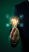 Businessman holding glowing light bulb with renewable energy icons representing sustainable innovation and green technology solutions for environmental progress.
