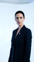 Professional businesswoman in navy suit with flag pin standing confidently in modern office environment for corporate leadership presentations.
