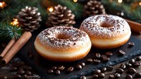 Fresh donuts dusted with powdered sugar on dark slate with pine cones, cinnamon sticks, coffee beans and Christmas lights creating festive holiday atmosphere.