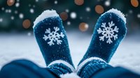 Cozy winter socks with snowflake pattern covered in fresh snow against blurred bokeh background. Festive holiday mood and warm comfort on cold winter day.