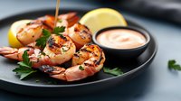 Grilled jumbo shrimp with fresh parsley garnish and creamy sauce served on black plate with lemon wedges, close up view of seafood appetizer.