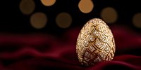 Ornate golden Easter egg with intricate floral pattern and jewels on luxurious red velvet background with soft bokeh lights creating festive atmosphere.