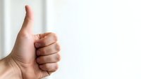 Hand showing thumbs up gesture against white background expressing approval, success and positive feedback for business presentations.