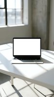 Open laptop with blank white screen on modern white desk in bright office space with natural window light for remote work and business presentations.