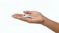 Hand holding silver house key on white background isolated for real estate property rental home ownership concept.