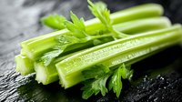 Fresh green celery stalks with leaves on wet black stone background, macro shot with water drops, healthy eating concept for food design.