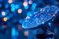 Glowing blue and gold bokeh lights reflected in curved glass surface create magical atmosphere for festive or celebration backgrounds.