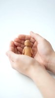 Protective hands gently holding small wooden figure symbolizing care, support and human protection on white background.