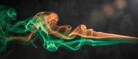 Abstract colorful smoke swirls in green and orange hues flowing against dark background for creative design projects and artistic compositions.